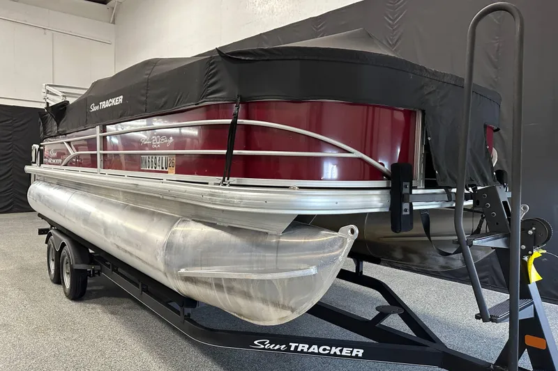 Slide: The Image of 2018 Sun Tracker SFB20 pontoon boat with cover on trailer in indoor setting. - 2
