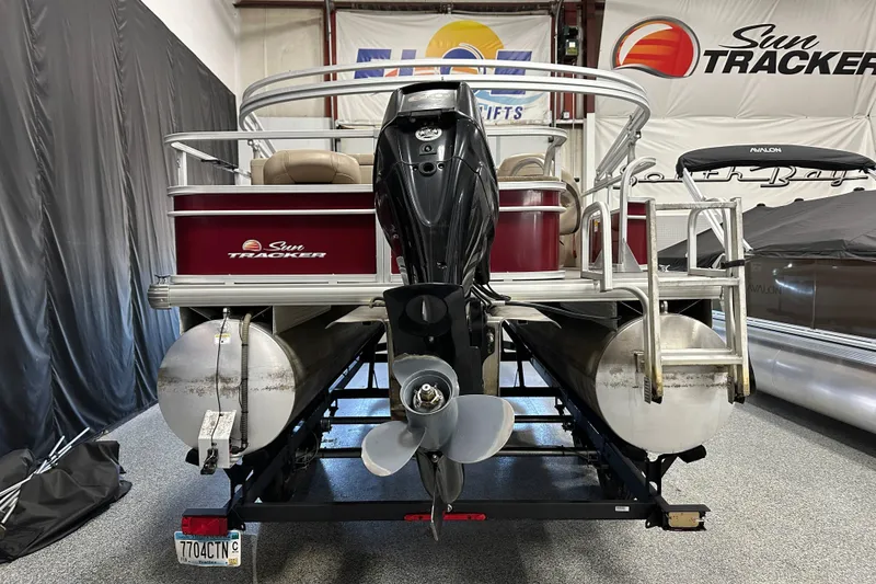 Slide: The Image of 2018 Sun Tracker SFB20 pontoon boat with outboard motor, displayed indoors. - 5