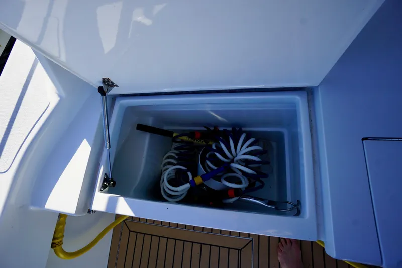 Slide: The Image of Open storage compartment on 2000 Venturer 44 boat with coiled hoses inside. - 104