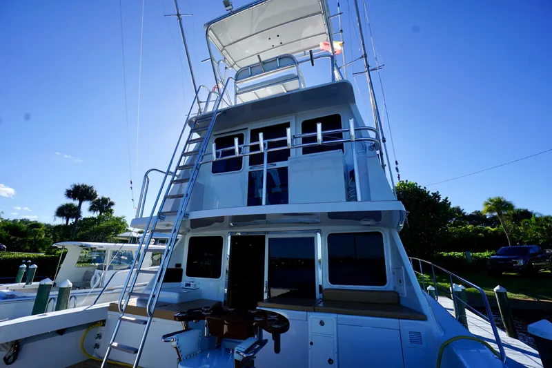 Slide: The Image of 2000 Venturer 44 yacht with upper deck and ladder, docked under clear blue sky. - 80