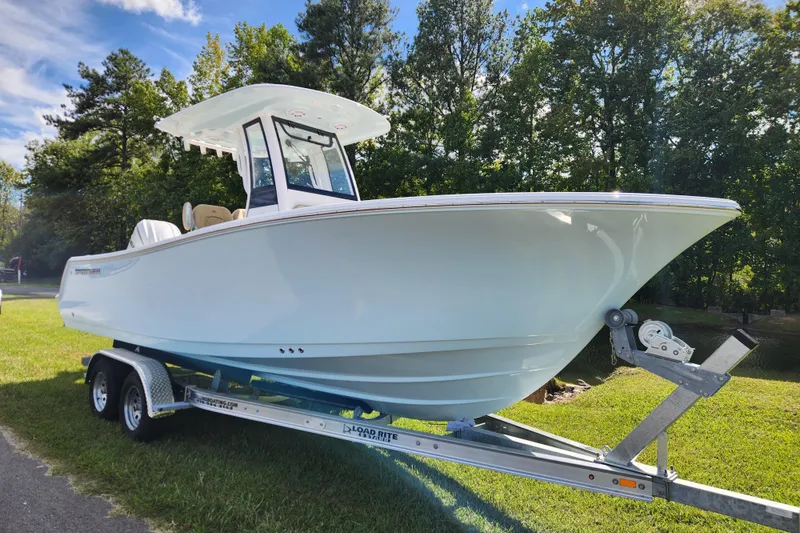 Slide: The Image of 2026 Sportsman Open 232 Center Console boat on trailer, surrounded by trees. - 1