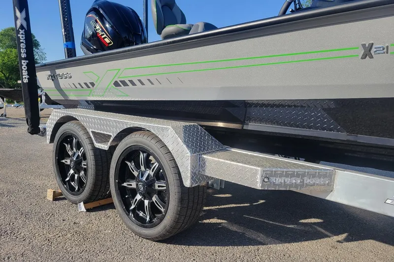 The Image of 2026 Xpress XR21 boat on trailer with stylish wheels and green accents. - 1