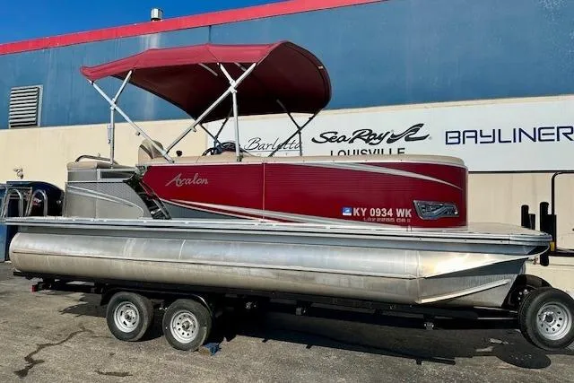 Slide: The Image of 2020 Avalon 220 Cruise pontoon boat with red canopy on trailer, parked outside dealership. - 1