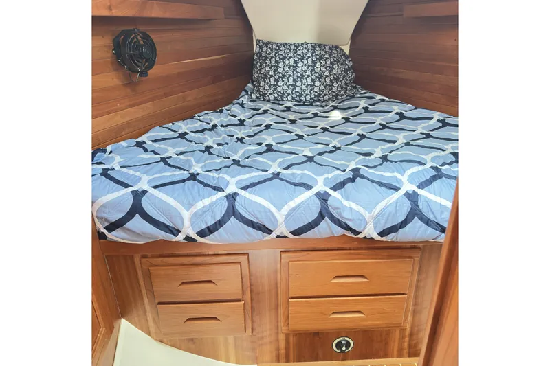 Slide: The Image of Cozy cabin interior of 2015 Tartan 3700 CCR with patterned bedding and wooden storage. - 3