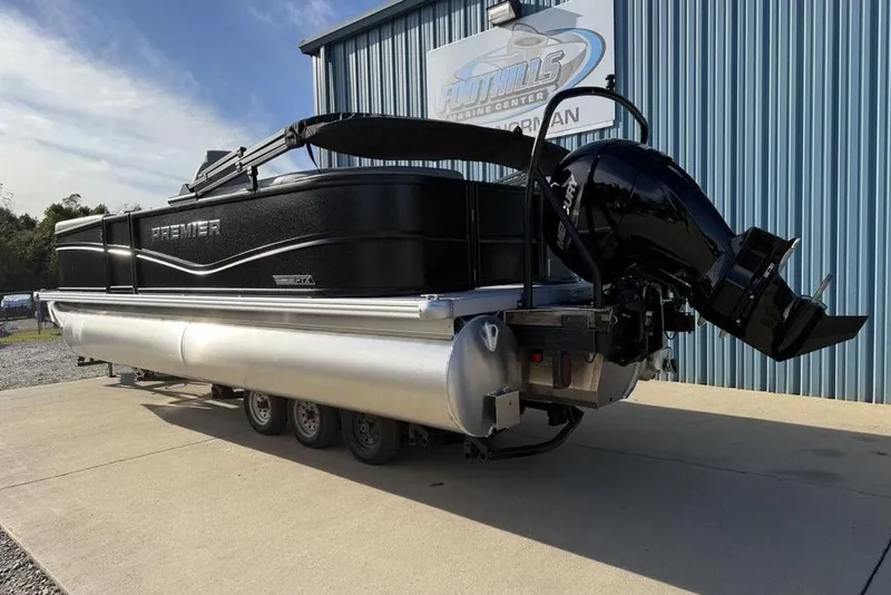 Slide: The Image of 2026 Premier 220 Sunscape RF pontoon boat with outboard motor, parked outside a marine center. - 6