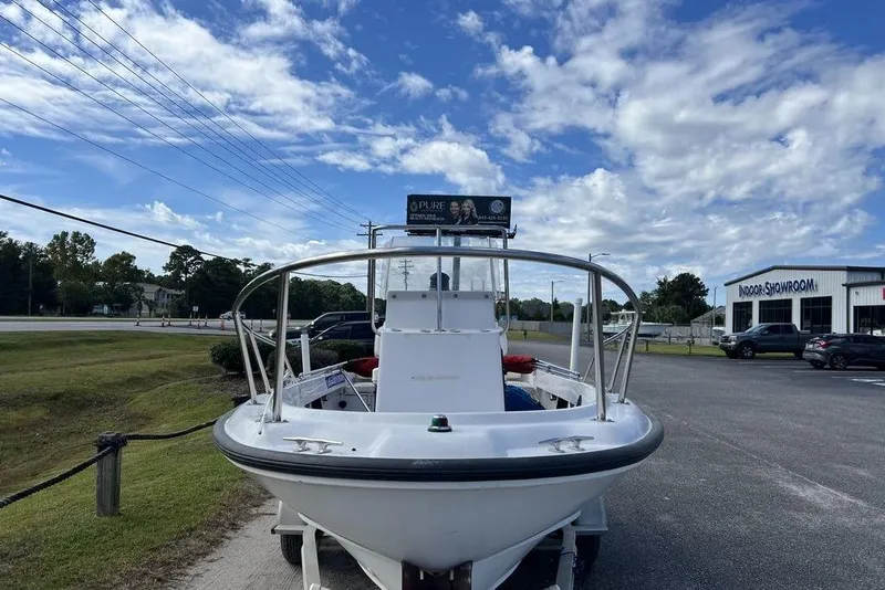 Slide: The Image of 1997 Boston Whaler Outrage 17 boat parked near showroom under blue sky. - 10
