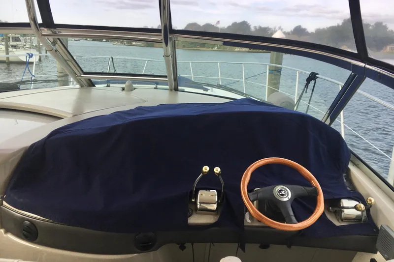 Slide: The Image of 2005 Sea Ray 420 Sundancer helm with covered dashboard and wooden steering wheel. - 14