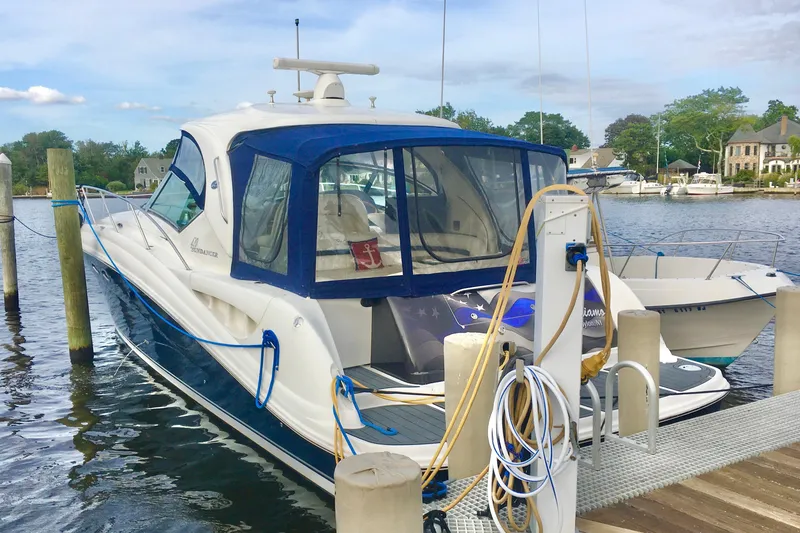 Slide: The Image of 2005 Sea Ray 420 Sundancer yacht docked at a marina, featuring a blue canopy. - 7