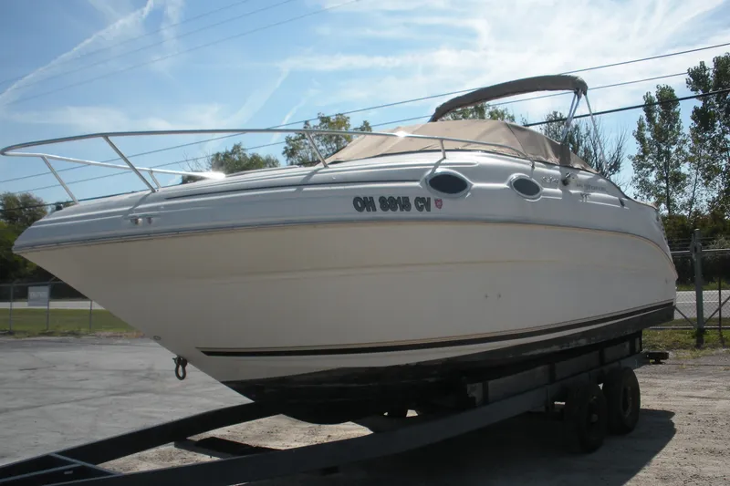 The Image of 2000 Sea Ray 240 Sundancer boat on trailer, parked outdoors. - 0