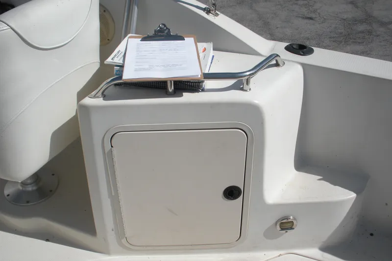 Slide: The Image of 2000 Sea Ray 240 Sundancer boat interior with storage compartment and clipboard. - 12
