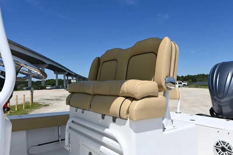 Slide: The Image of 2023 Clark Sound 24 boat with tan seating and steering wheel, parked near a bridge. - 7