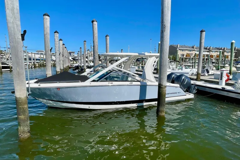 Slide: The Image of 2023 Chaparral 280 OSX boat docked in a marina under clear blue skies. - 21