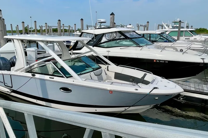 Slide: The Image of 2023 Chaparral 280 OSX boat docked at a marina, showcasing sleek design and modern features. - 22