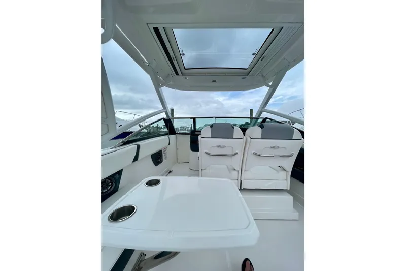 Slide: The Image of 2023 Chaparral 280 OSX boat interior with seating and table under a skylight. - 27