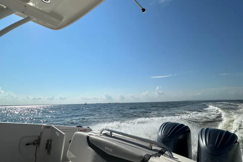 Slide: The Image of 2023 Chaparral 280 OSX boat cruising on open water under clear blue sky. - 28
