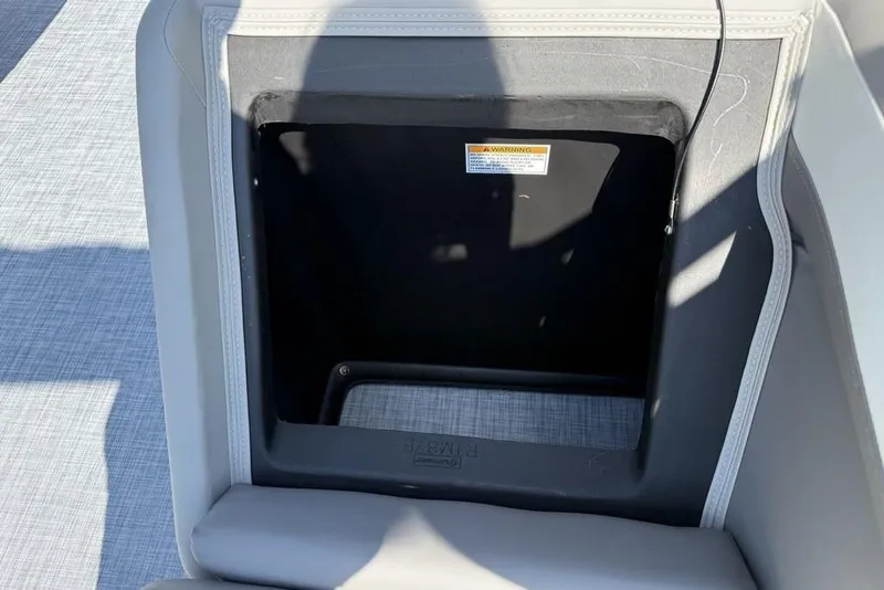 Slide: The Image of 2026 Premier 220 Sunscape RF storage compartment with warning label, featuring gray upholstery. - 21