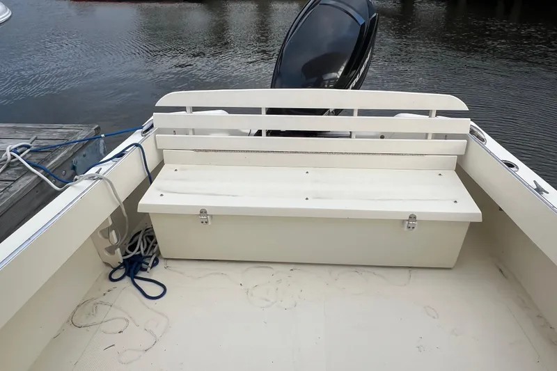 Slide: The Image of 2018 Seaway 21 Seafarer Cuddy boat interior with bench and motor, docked by water. - 8