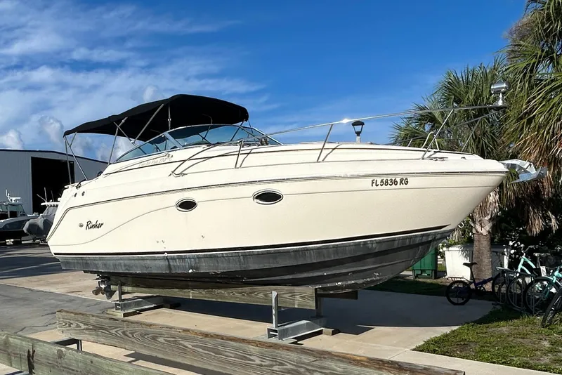 The Image of 2000 Rinker 270 Fiesta Vee boat on display, featuring a sleek design and black canopy. - 0