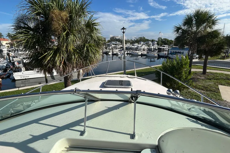 Slide: The Image of 2000 Rinker 270 Fiesta Vee boat docked near palm trees and marina. - 10