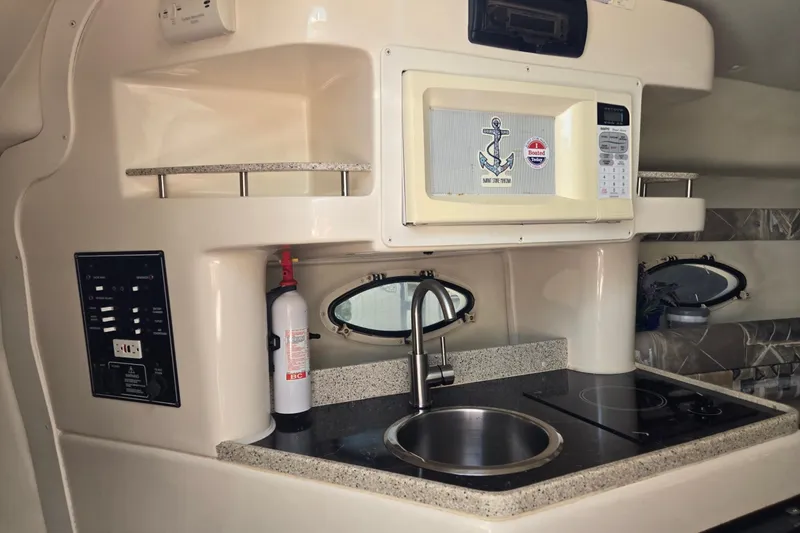 Slide: The Image of 2000 Rinker 270 Fiesta Vee boat kitchen with microwave, sink, and stove. - 17