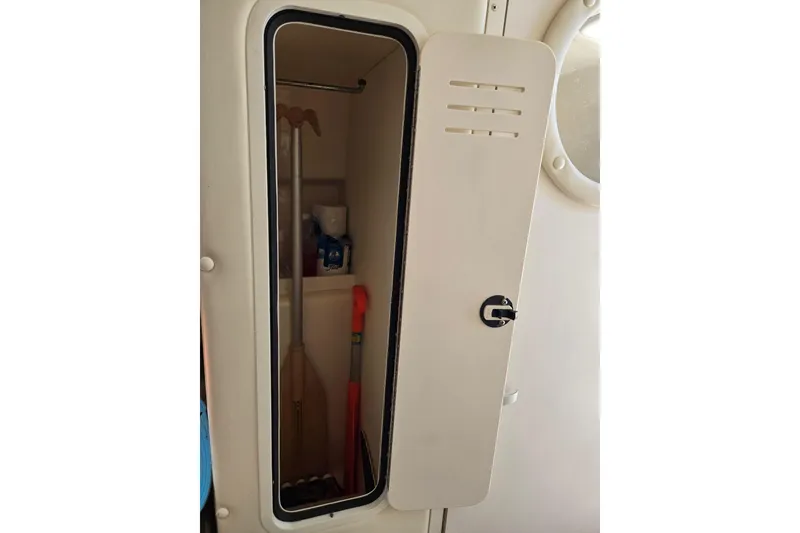 Slide: The Image of Storage compartment on 2000 Rinker 270 Fiesta Vee boat, containing paddles and supplies. - 18