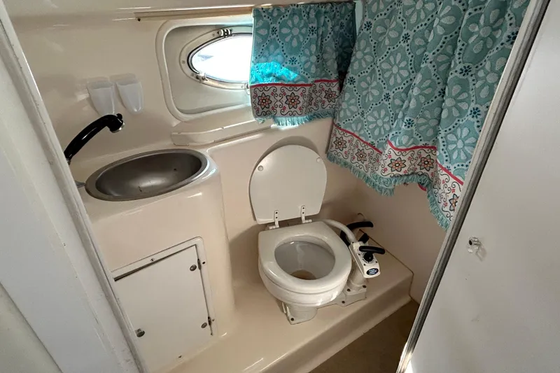 Slide: The Image of 2000 Rinker 270 Fiesta Vee boat bathroom with sink, toilet, and floral curtains. - 23