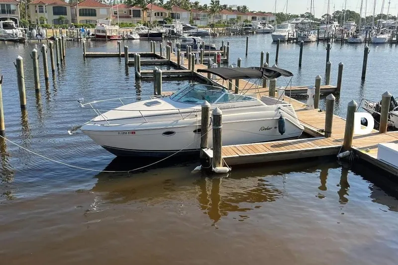 Slide: The Image of 2000 Rinker 270 Fiesta Vee boat docked at marina, surrounded by water and other vessels. - 3