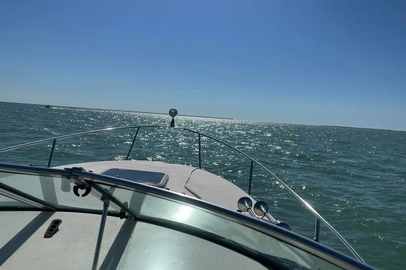 Slide: The Image of 2000 Rinker 270 Fiesta Vee boat cruising on sparkling blue water under clear sky. - 4