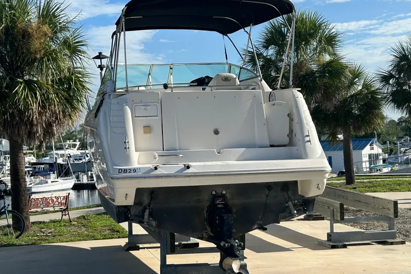 Slide: The Image of 2000 Rinker 270 Fiesta Vee boat on trailer, surrounded by palm trees and marina. - 6