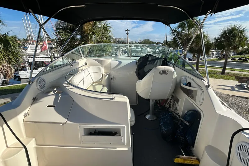 Slide: The Image of 2000 Rinker 270 Fiesta Vee boat interior with seating and helm, docked near palm trees. - 9