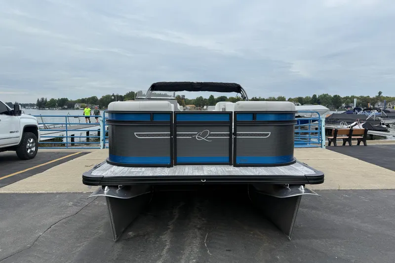 Slide: The Image of 2026 Qwest E-CLASS 22 RLS pontoon boat docked by a lakeside marina. - 3