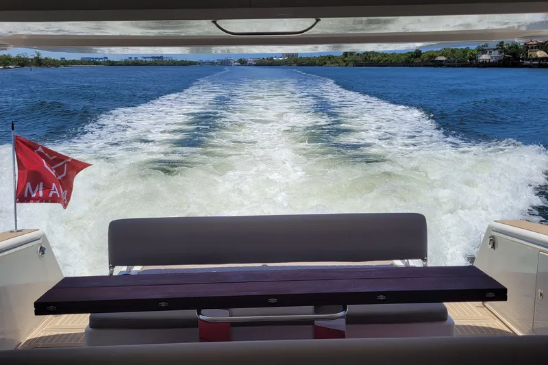 Slide: The Image of Wake view from a 2025 Makai M37 boat, featuring a red flag and serene waters. - 92