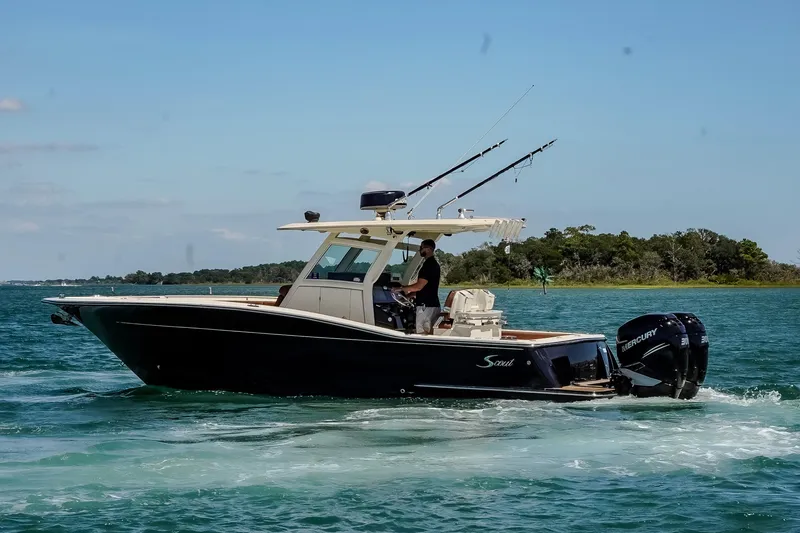 Slide: The Image of 2017 Scout 300 LXF boat cruising on clear blue water with fishing rods. - 10