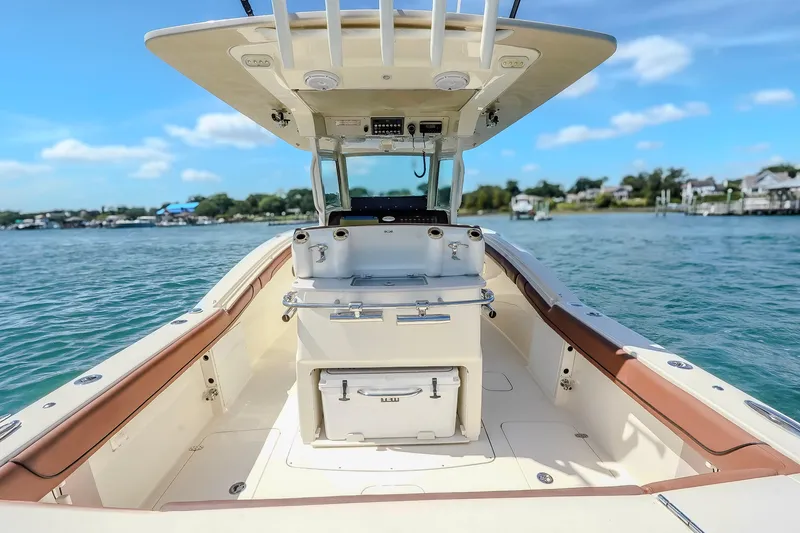 Slide: The Image of 2017 Scout 300 LXF boat interior with helm, on calm water under blue sky. - 13