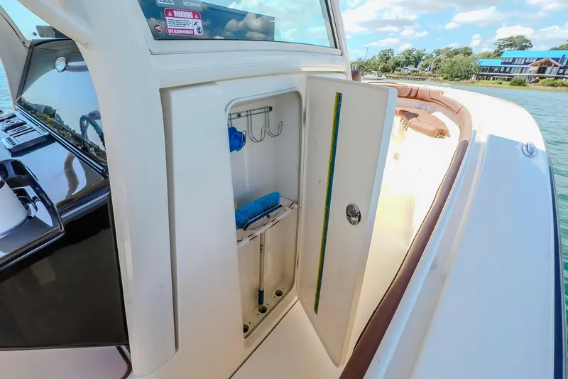 Slide: The Image of 2017 Scout 300 LXF boat storage compartment with cleaning tools, docked by the water. - 34