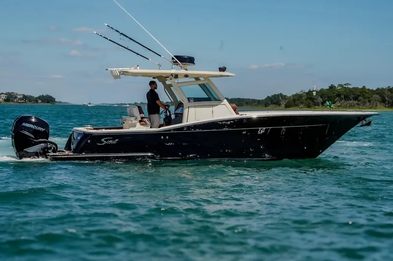 Slide: The Image of 2017 Scout 300 LXF boat cruising on clear blue water with fishing rods. - 6