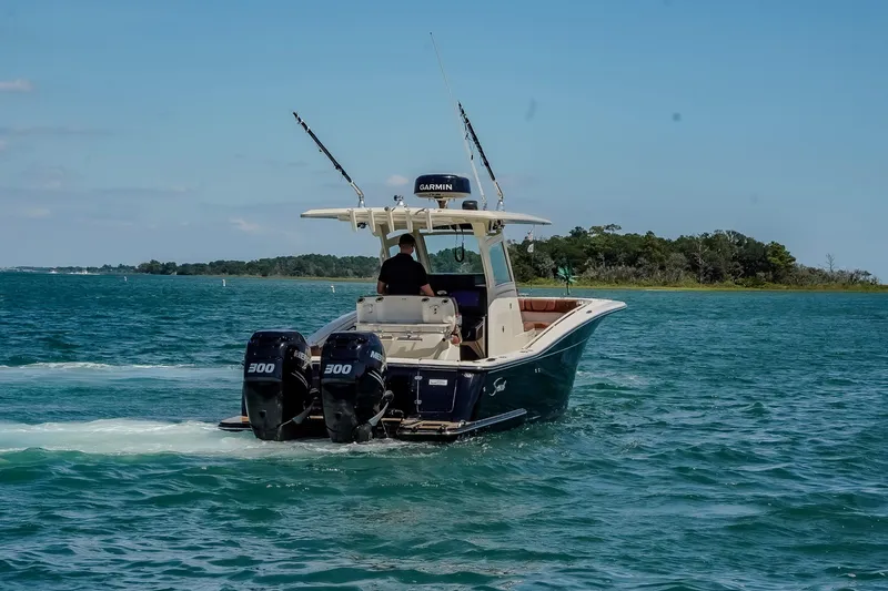 Slide: The Image of 2017 Scout 300 LXF boat cruising on blue water with dual engines. - 7