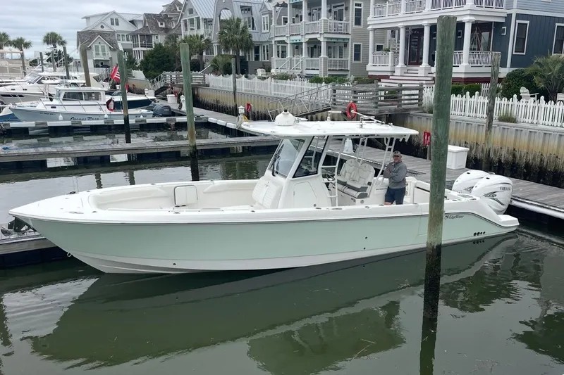 Slide: The Image of 2020 Edgewater 340CC boat docked in a marina with waterfront homes in the background. - 9