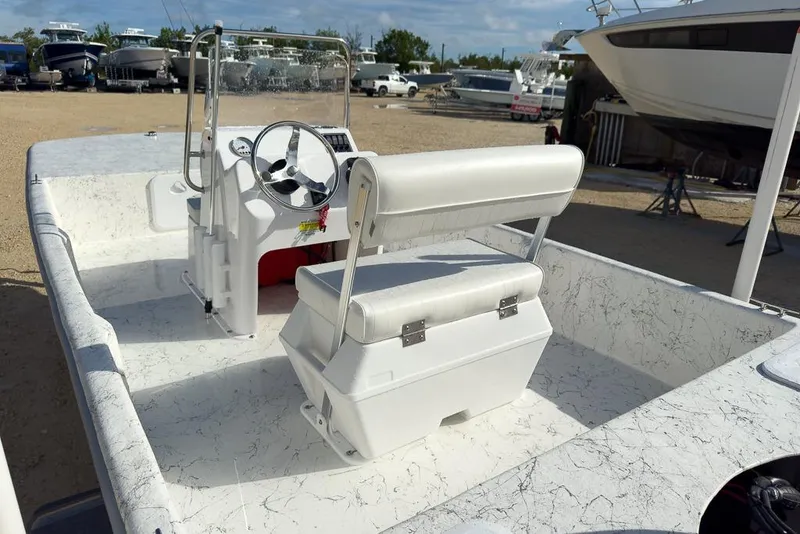 Slide: The Image of 2026 Coastal Skiff 171 boat interior with steering wheel and seating, docked among other boats. - 6