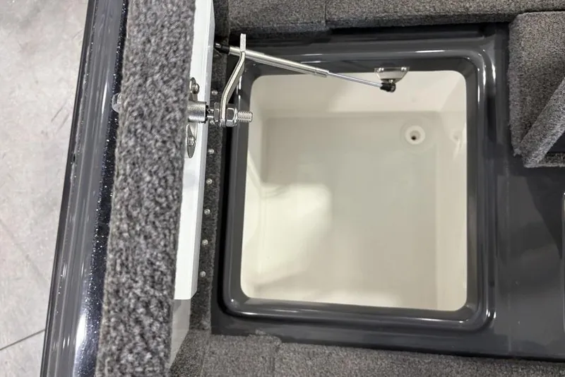 Slide: The Image of Open storage compartment in 2024 Phoenix 919 Pro XP boat, featuring carpeted interior and metal latch. - 24