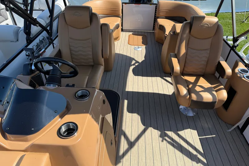 Slide: The Image of 2025 SunCatcher Fusion 324RC boat interior with tan leather seating and steering console. - 2