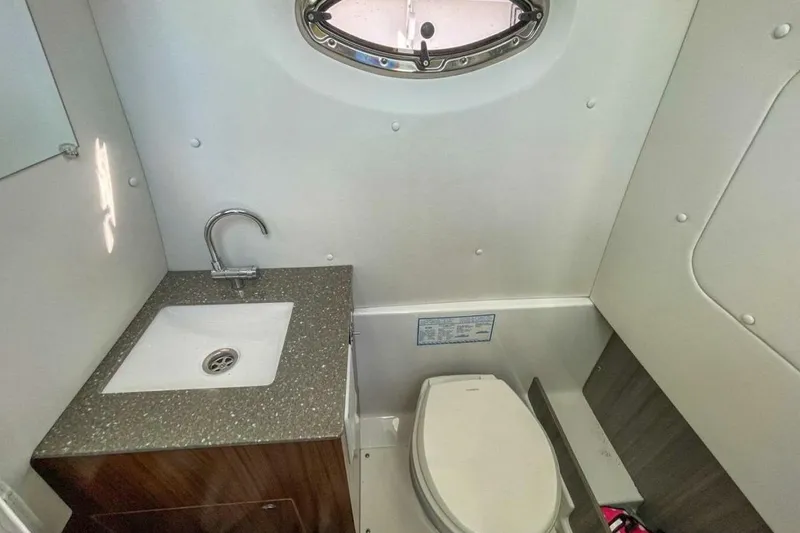 Slide: The Image of 2021 Wellcraft 302 Scarab boat bathroom with sink, toilet, and porthole window. - 7