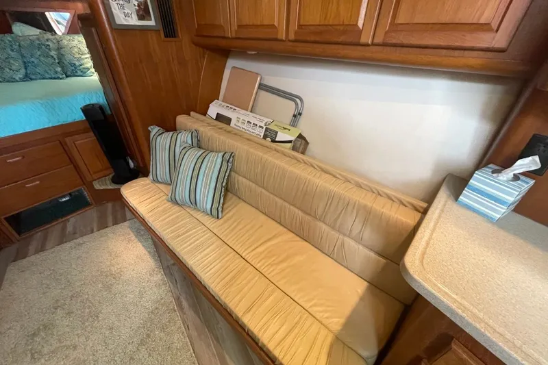 Slide: The Image of 1997 Luhrs 36 SX interior with beige seating, striped pillows, and wooden cabinetry. - 19