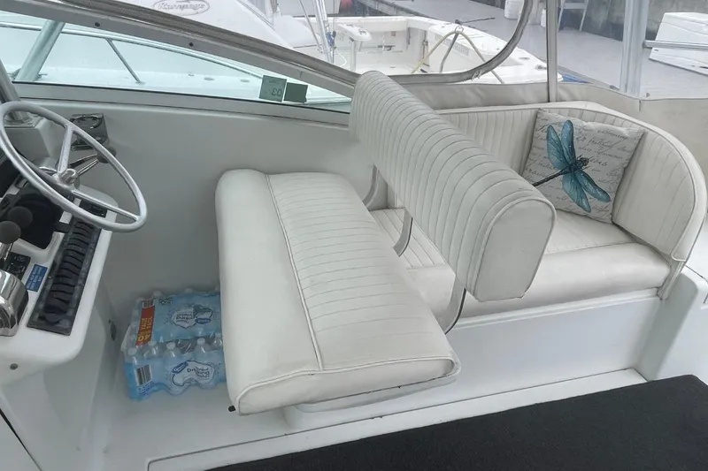 Slide: The Image of 1997 Luhrs 36 SX boat interior with white seating, steering wheel, and decorative pillow. - 25