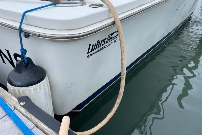 Slide: The Image of 1997 Luhrs 36 SX boat docked, showing logo and water reflection. - 46