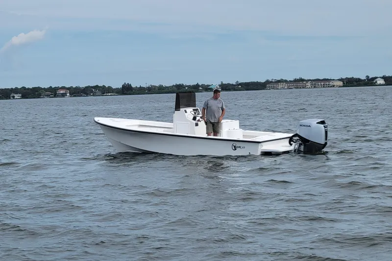 Slide: The Image of 2025 C-Hawk 23CC boat on water with person standing, Honda outboard motor. - 7