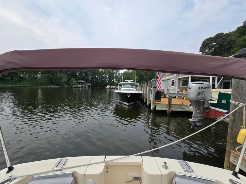 Slide: The Image of 2001 Mainship Pilot 30 Sedan docked near waterfront homes, with a Honda outboard motor visible. - 10