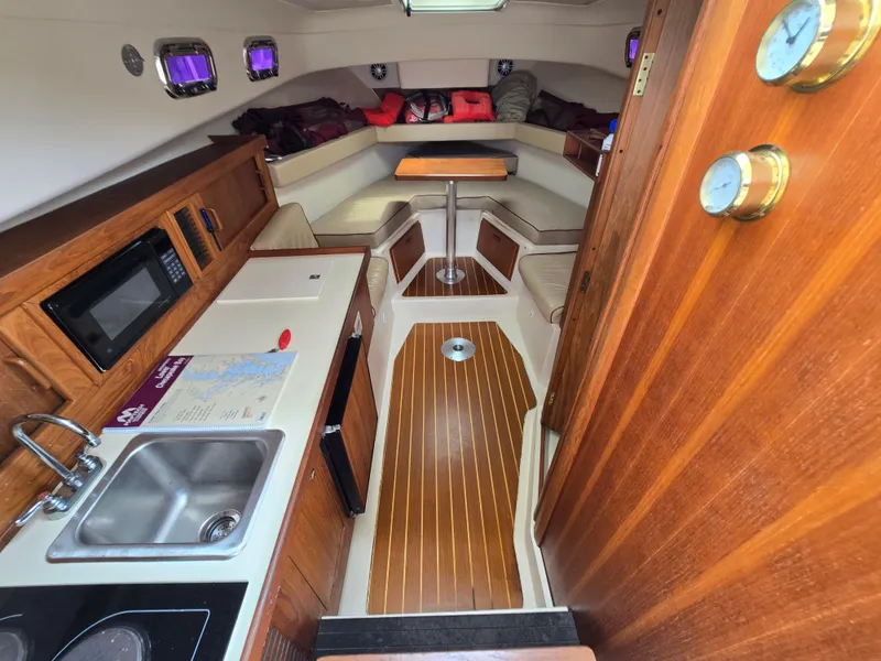 Slide: The Image of 2001 Mainship Pilot 30 Sedan interior with kitchenette, seating, and wood accents. - 19