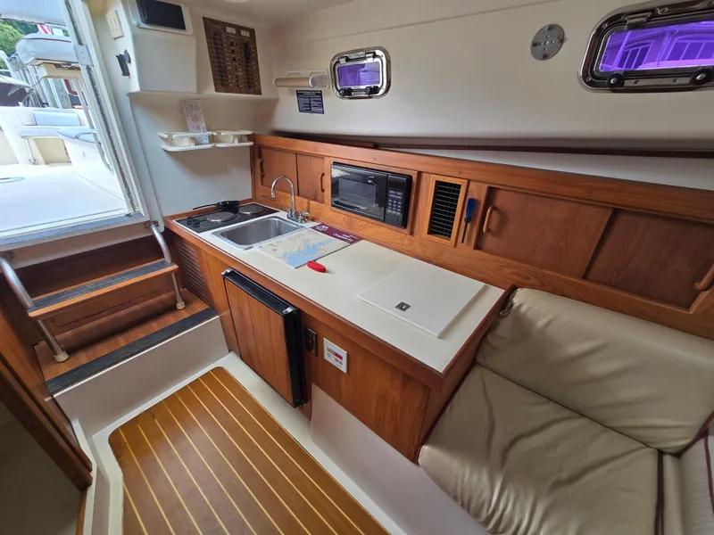 Slide: The Image of 2001 Mainship Pilot 30 Sedan interior with kitchenette, sink, microwave, and seating area. - 21