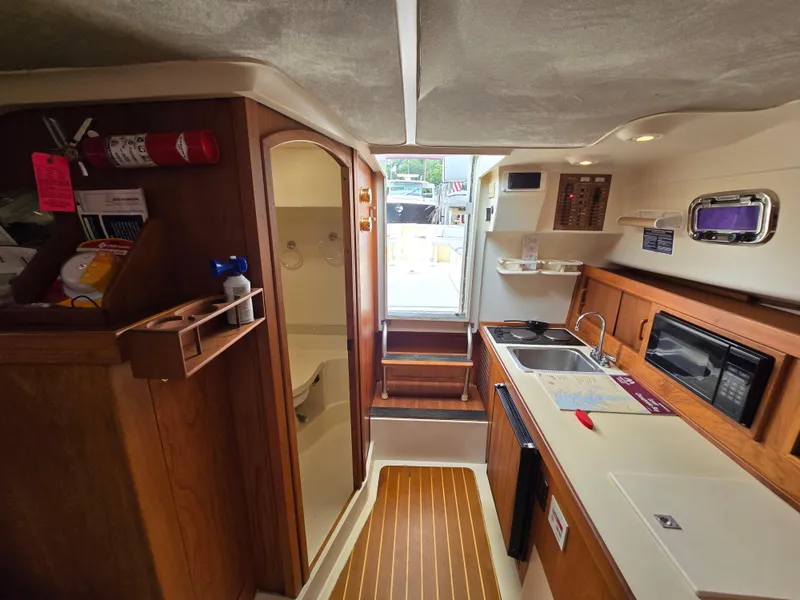 Slide: The Image of Interior of 2001 Mainship Pilot 30 Sedan with kitchenette and wooden cabinetry. - 24